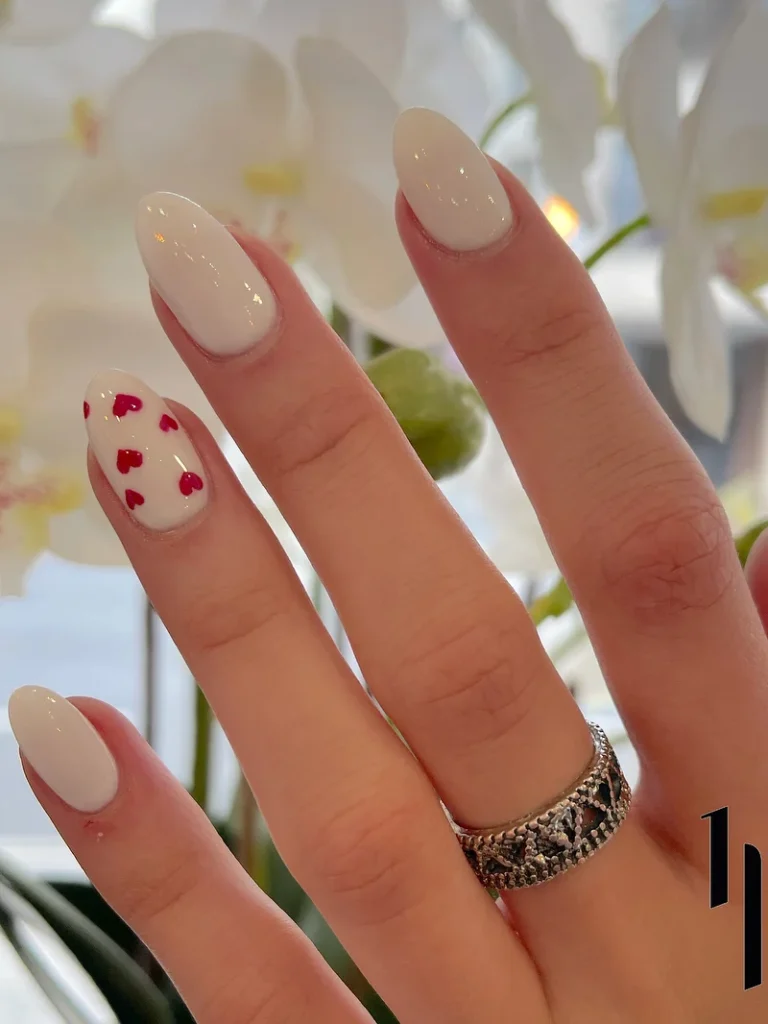 white gel nails with small red heart nail art design at honu nails