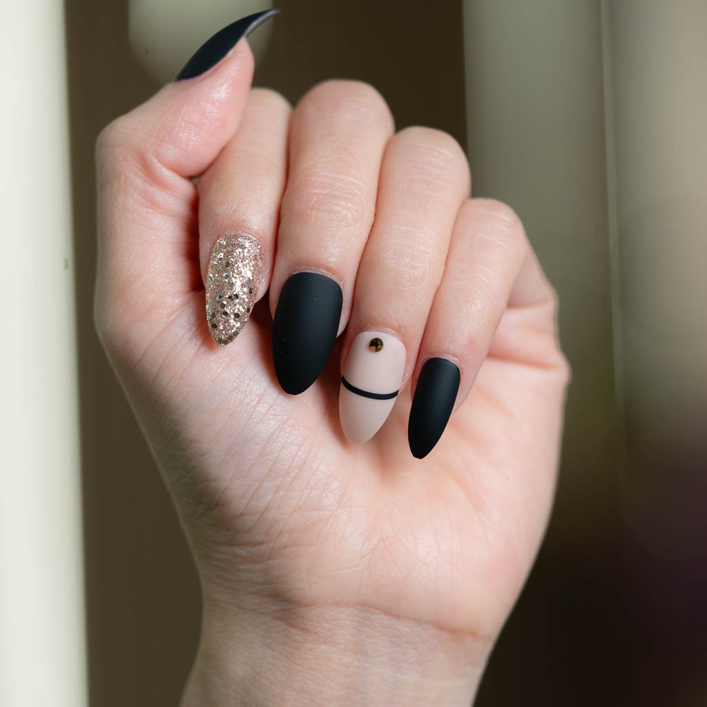 Black and nude luxury nail art at H’ONU with matte finish, gold detail and glitter accent nail design