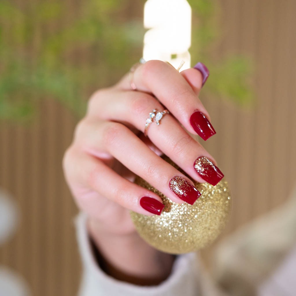 Red gel nails with gold glitter accent at H’ONU for a festive and elegant holiday manicure