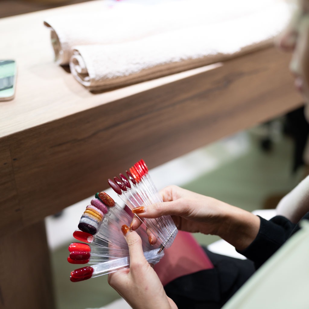 Choosing nail colours at H’ONU with gel polish samples and variety of manicure shades